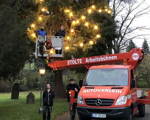 Beleuchtungsteam und Hubwagen vor dem fertig geschmückten Baum