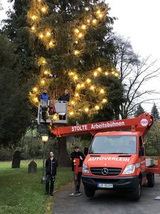 Beleuchtungsteam und Hubwagen vor dem fertig geschmückten Baum